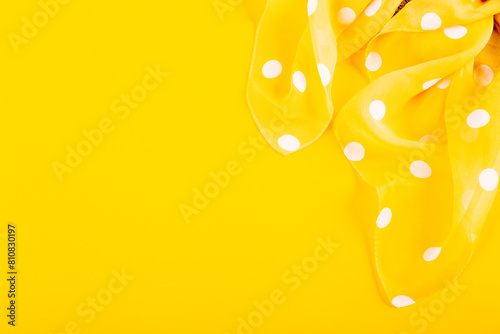 Silk patch of white polka dot fabric on a yellow background. The concept of summer holidays, sewing hobby, handmade workshop, repairing clothes, fabric store card. Bright woman accessory. Copy space