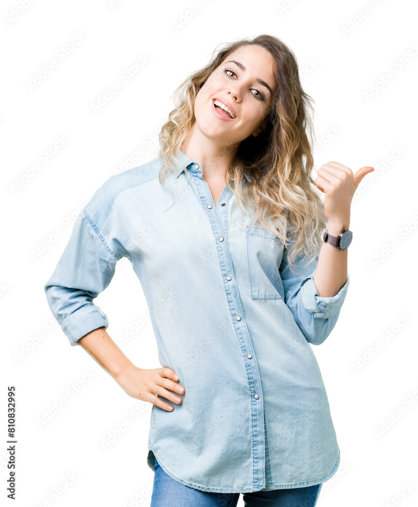 Beautiful young blonde woman over isolated background smiling with happy face looking and pointing to the side with thumb up. Beautiful young blonde woman over isolated background smiling with happy face looking and pointing to the side with thumb up.