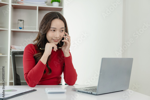 Happy young Asian employee sitting at table and working with computer and calculator, financial documents Calculate the legal company's tax rate financial accounts on the computer.