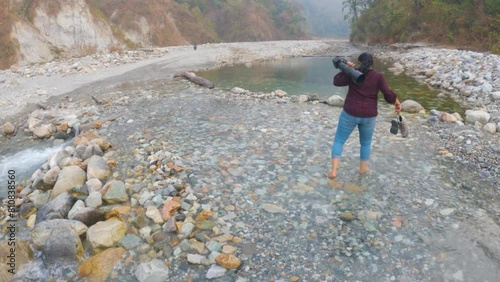 Choto Mahakal, Buxa Tiger Reserve, Alipur Duiar, West Bengal, India, 3rd March, 2024: A female traveler enjoying walking on a river at Buxa Tiger Reserve going to famous Mahakaal cave. photo