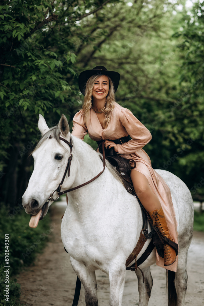 Fototapeta premium Beautiful blonde girl in a long dress with a white horse