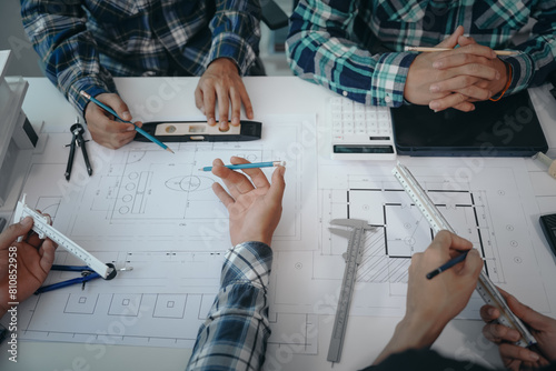 Team of engineers in a meeting, drawing blueprints for condo, apartment, and house construction. Negotiating costs with contractors, bidding, bargaining, and cooperating on construction sites.