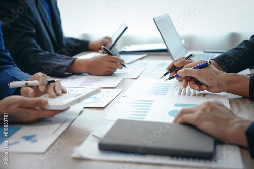 A professional business team meeting in formal suits, working at desks with financial papers, calculators, and laptops. Close-up of hands. Discussion on revenue, brand, sales, agenda, capital