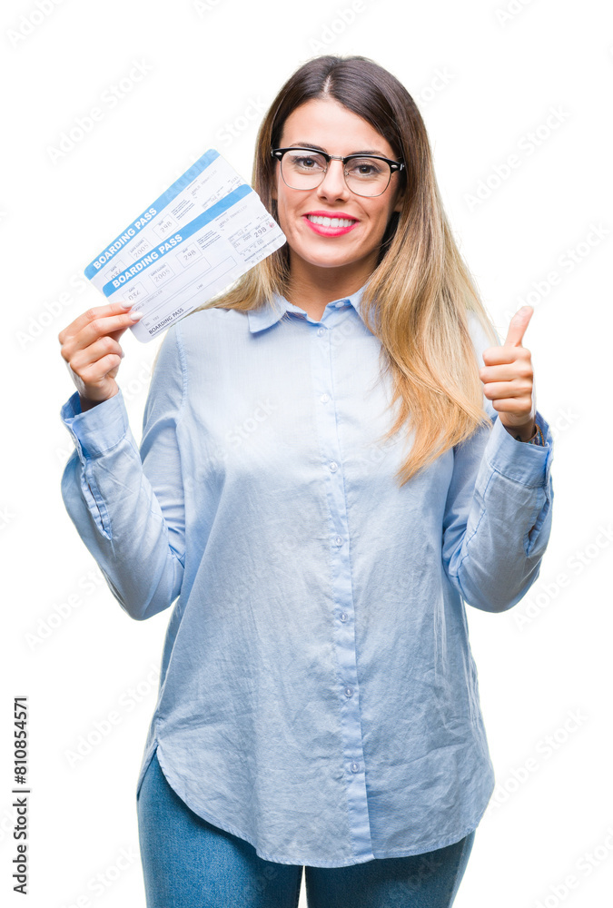 Young beautiful woman holding boarding pass over isolated background happy with big smile doing ok sign, thumb up with fingers, excellent sign Young beautiful woman holding boarding pass over isolated background happy with big smile doing ok sign, thumb up with fingers, excellent sign