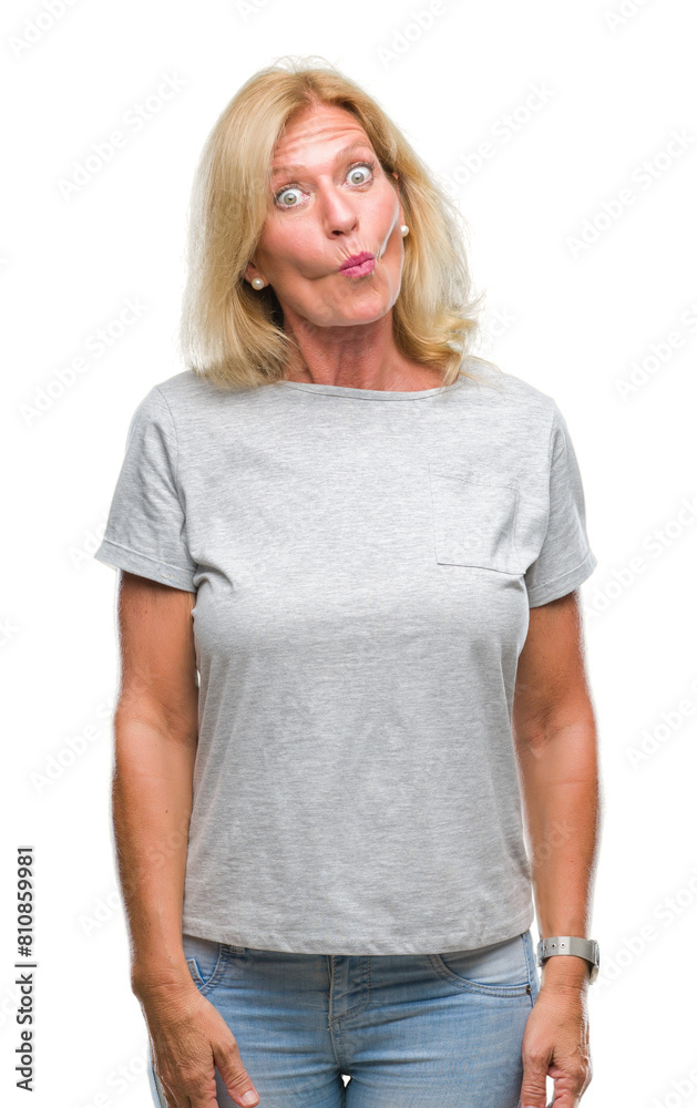 Middle age blonde woman over isolated background making fish face with lips, crazy and comical gesture. Funny expression. Middle age blonde woman over isolated background making fish face with lips, crazy and comical gesture. Funny expression.