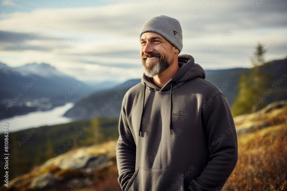 Portrait of a jovial man in his 40s sporting a comfortable hoodie isolated on panoramic mountain vista Portrait of a jovial man in his 40s sporting a comfortable hoodie isolated on panoramic mountain vista