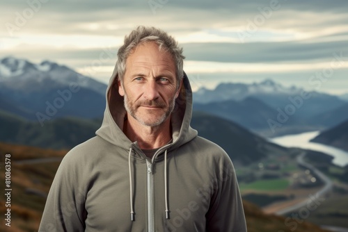 Portrait of a blissful man in his 50s wearing a zip-up fleece hoodie in panoramic mountain vista