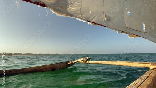 4K authentic wooden sailing fishing boat heading for open seas with rugged sail. Traveling, fishing lifestyle, tropical environment, indigenous peoples and remote places concept. Zanzibar, Tanzania. photo