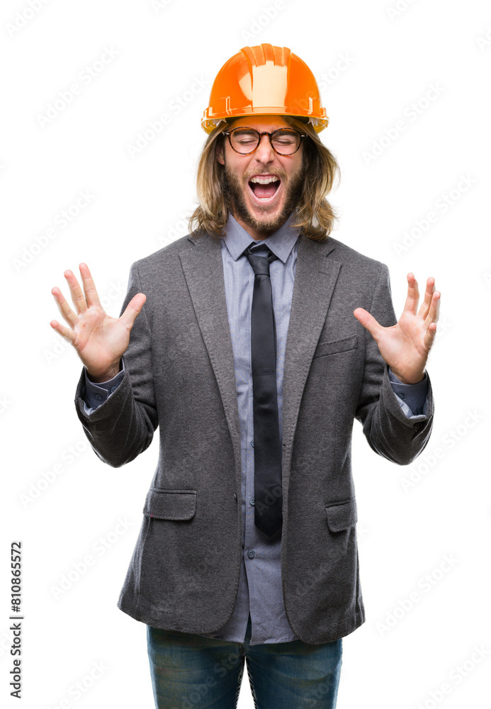 Young handsome architec man with long hair wearing safety helmet over isolated background celebrating mad and crazy for success with arms raised and closed eyes screaming excited. Winner concept Young handsome architec man with long hair wearing safety helmet over isolated background celebrating mad and crazy for success with arms raised and closed eyes screaming excited. Winner concept