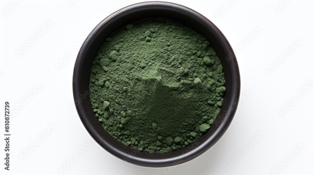 A bowl of green powder is sitting on a white background A bowl of green powder is sitting on a white background