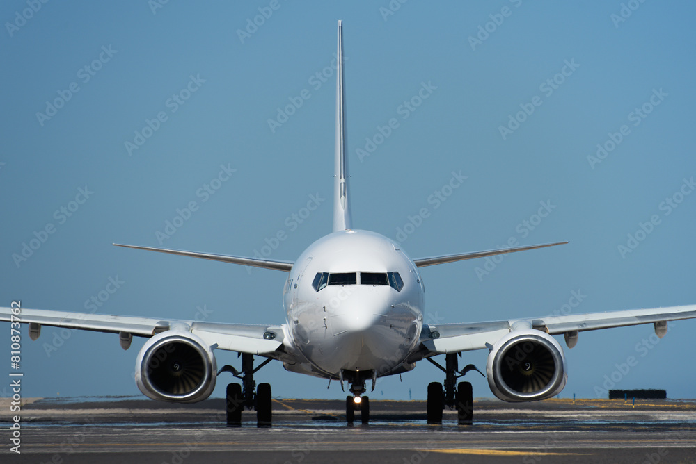 Naklejka premium White passenger jet plane taxiing along the runway in the airport