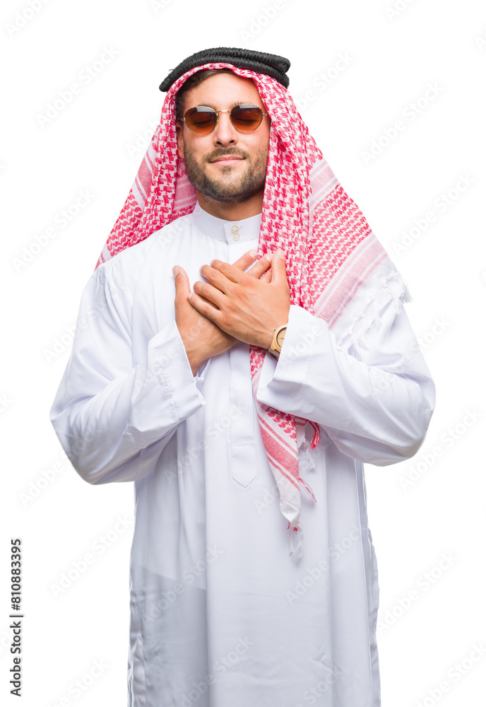 Young handsome man wearing keffiyeh over isolated background smiling with hands on chest with closed eyes and grateful gesture on face. Health concept.