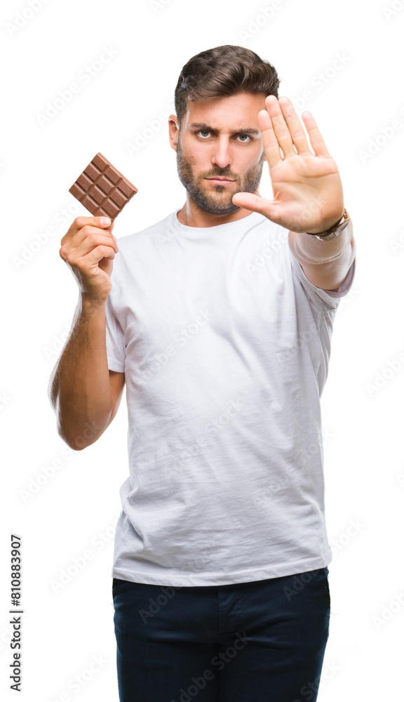 Young handsome man eating chocolate bar over isolated background with open hand doing stop sign with serious and confident expression, defense gesture