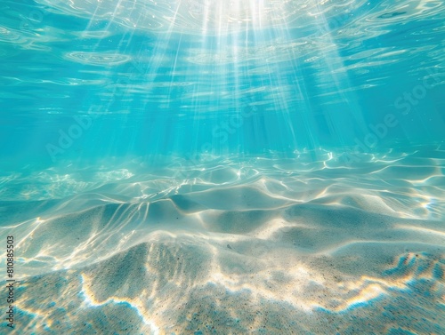 Sunlight shining through azure water on sandy ocean floor