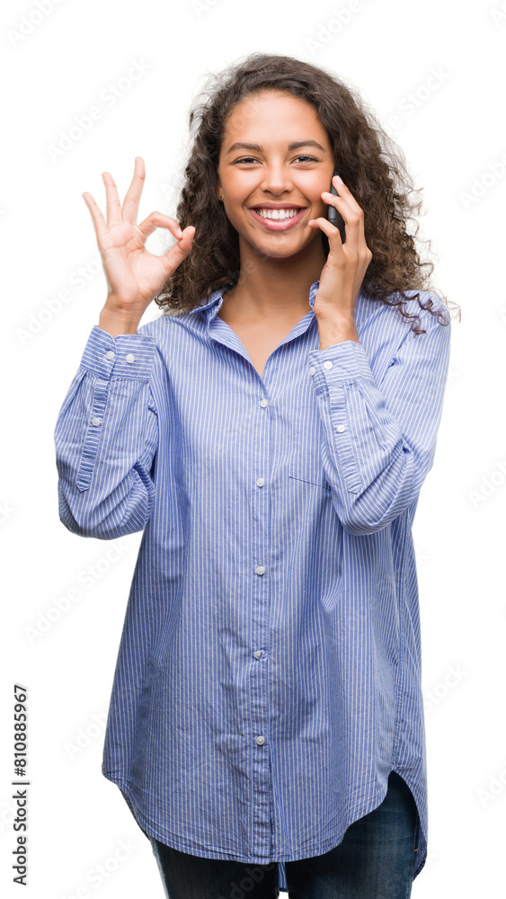Young hispanic woman using smartphone doing ok sign with fingers, excellent symbol Young hispanic woman using smartphone doing ok sign with fingers, excellent symbol