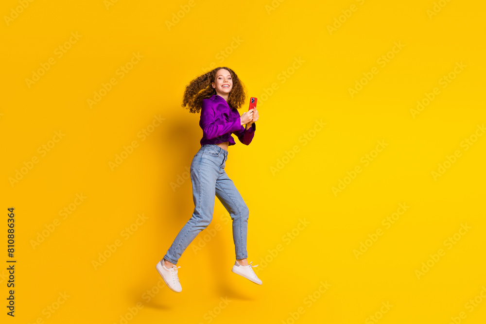Full length photo of lovely young lady running hold gadget dressed stylish violet garment isolated on yellow color background