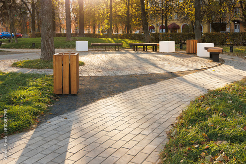 Different types of surfaces in the park. Path made of rectangular paving slabs. Round seating area made of rounded paving slabs. Covering with screenings (coarse black sand).