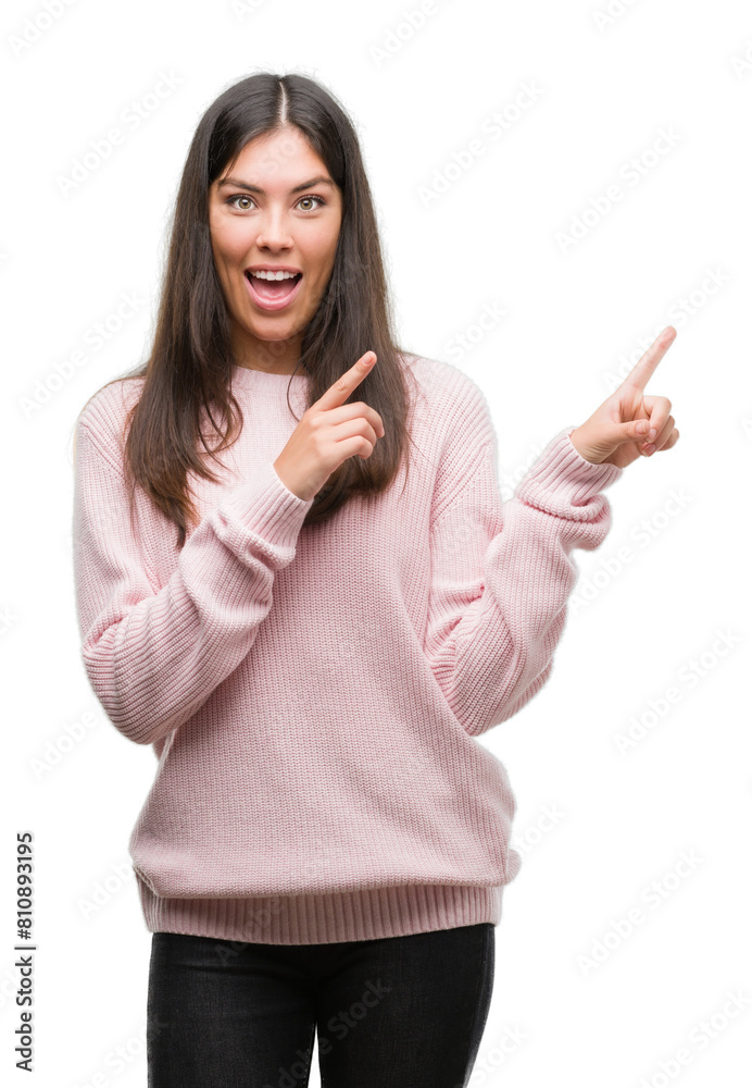 Young beautiful hispanic woman wearing a sweater smiling and looking at the camera pointing with two hands and fingers to the side. Young beautiful hispanic woman wearing a sweater smiling and looking at the camera pointing with two hands and fingers to the side.