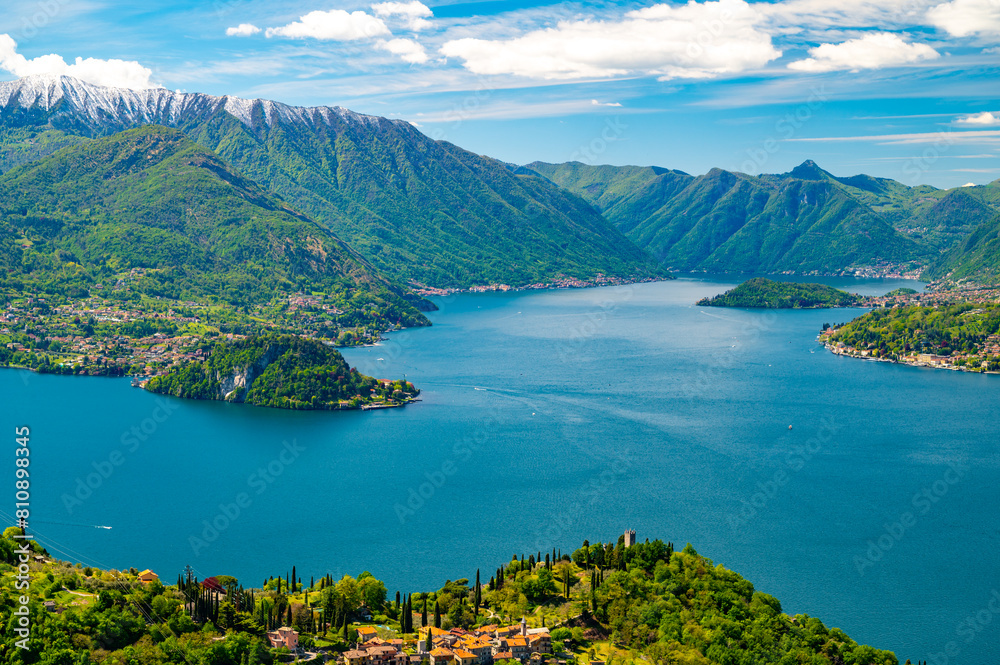 Lake Como, seen from Perledo, with Varenna, Bellagio, Vezio Castle, Punta Balbianello, on a spring day, with snow-capped mountains.