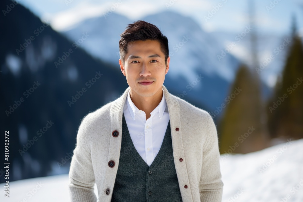 Portrait of a glad asian man in his 30s wearing a chic cardigan over pristine snowy mountain Portrait of a glad asian man in his 30s wearing a chic cardigan over pristine snowy mountain