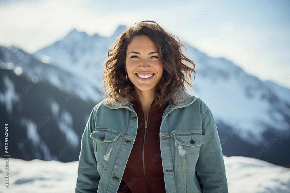 Portrait of a smiling woman in her 40s sporting a rugged denim jacket isolated in pristine snowy mountain Portrait of a smiling woman in her 40s sporting a rugged denim jacket isolated in pristine snowy mountain