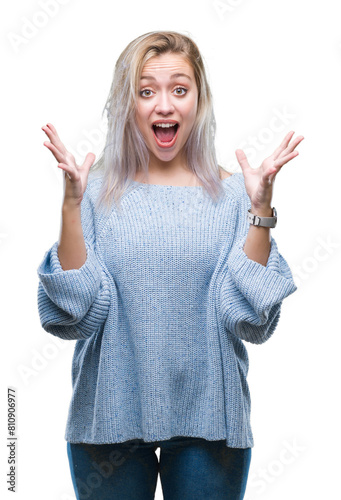 Young blonde woman wearing winter sweater over isolated background celebrating crazy and amazed for success with arms raised and open eyes screaming excited. Winner concept