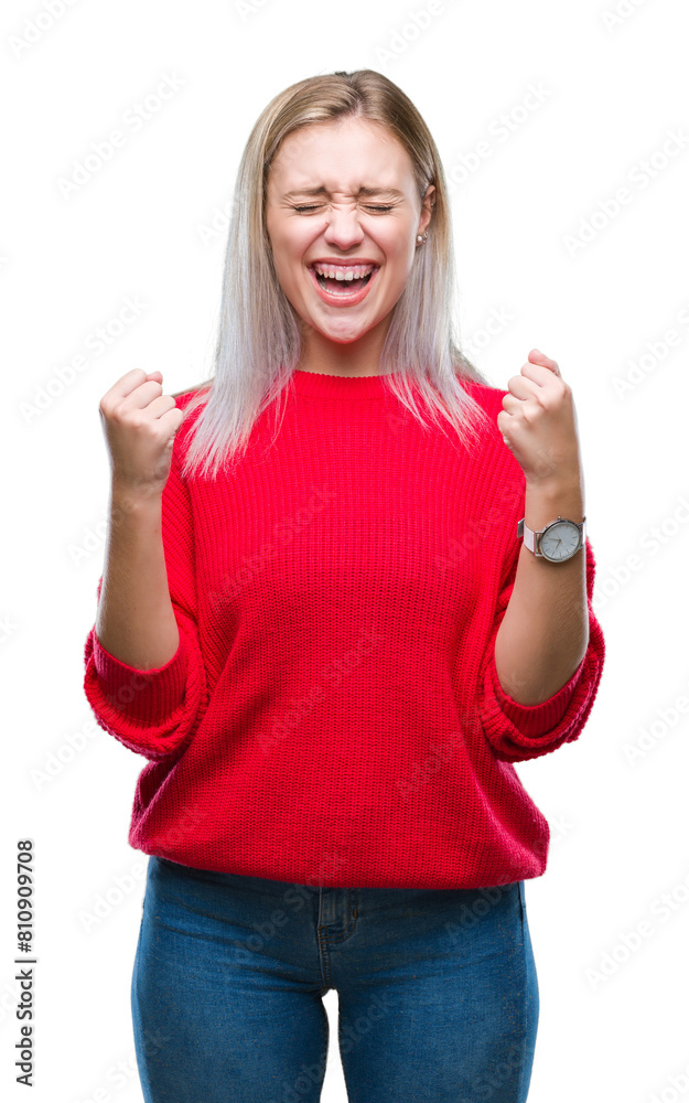 Young blonde woman wearing winter sweater over isolated background excited for success with arms raised celebrating victory smiling. Winner concept.