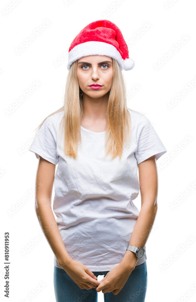 Young beautiful blonde woman christmas hat over isolated background with serious expression on face. Simple and natural looking at the camera. Young beautiful blonde woman christmas hat over isolated background with serious expression on face. Simple and natural looking at the camera.