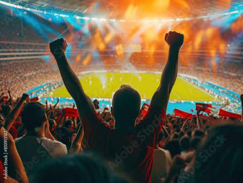 Passionate sports fans at a stadium match raise arms, cheer, applaud, and shout, infectiously inspiring their team. Their contagious enthusiasm fuels the support for their favorite players in the ques photo