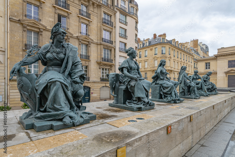 A row of allegorical statues representing continents on the terrace of the Orsay Museum, with visitors in the background.