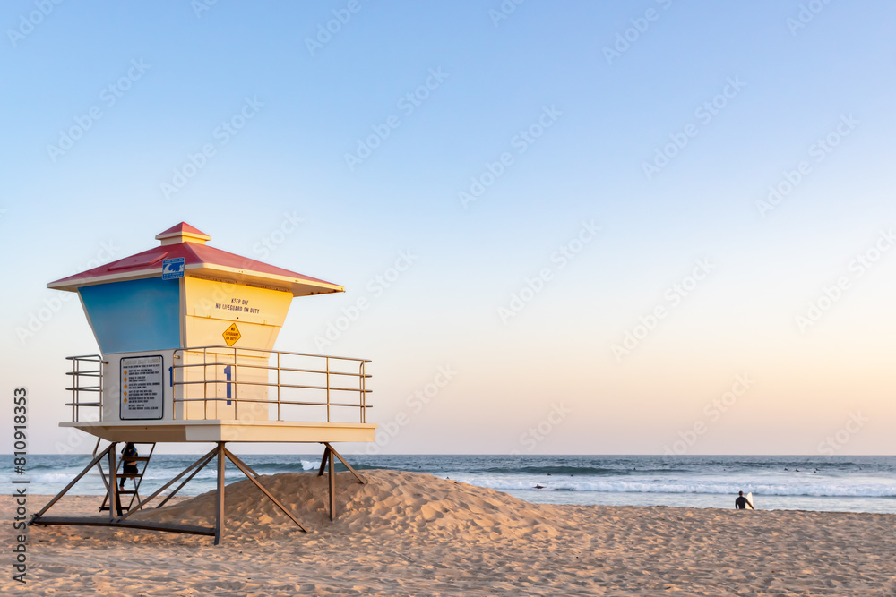 Overview of Beach, Pastel Color Sky Near Sunset with Lifeguard Tower in Midground, Waves and Clear Sky in Background, California, USA, horizontal, distant people Overview of Beach, Pastel Color Sky Near Sunset with Lifeguard Tower in Midground, Waves and Clear Sky in Background, California, USA, horizontal, distant people