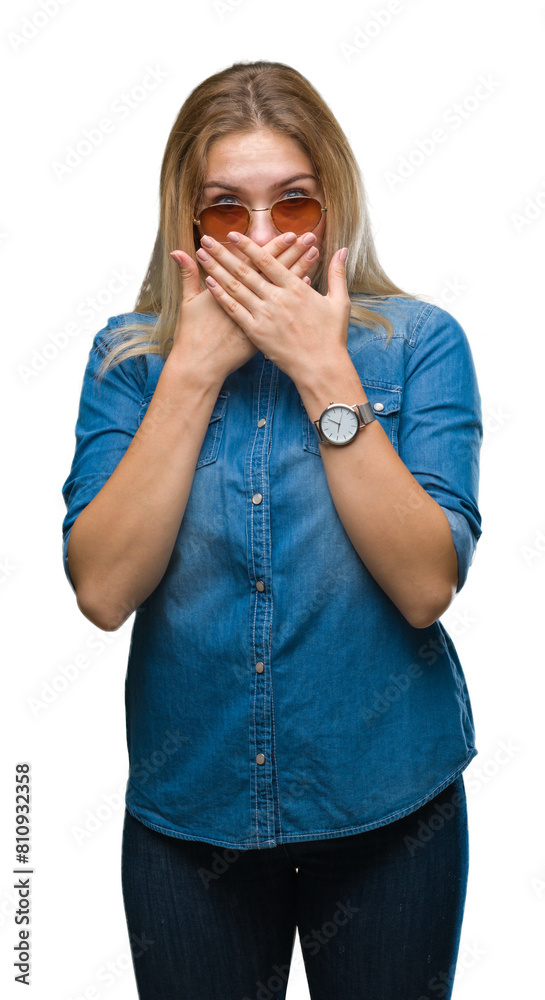 Young caucasian woman wearing sunglasses over isolated background shocked covering mouth with hands for mistake. Secret concept. Young caucasian woman wearing sunglasses over isolated background shocked covering mouth with hands for mistake. Secret concept.