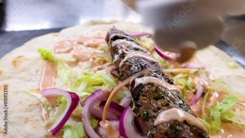 Kebab drizzled with sauce in slow motion on a flatbread slow motion