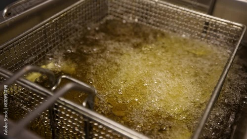 Chips in fryer being deep fried, slow motion