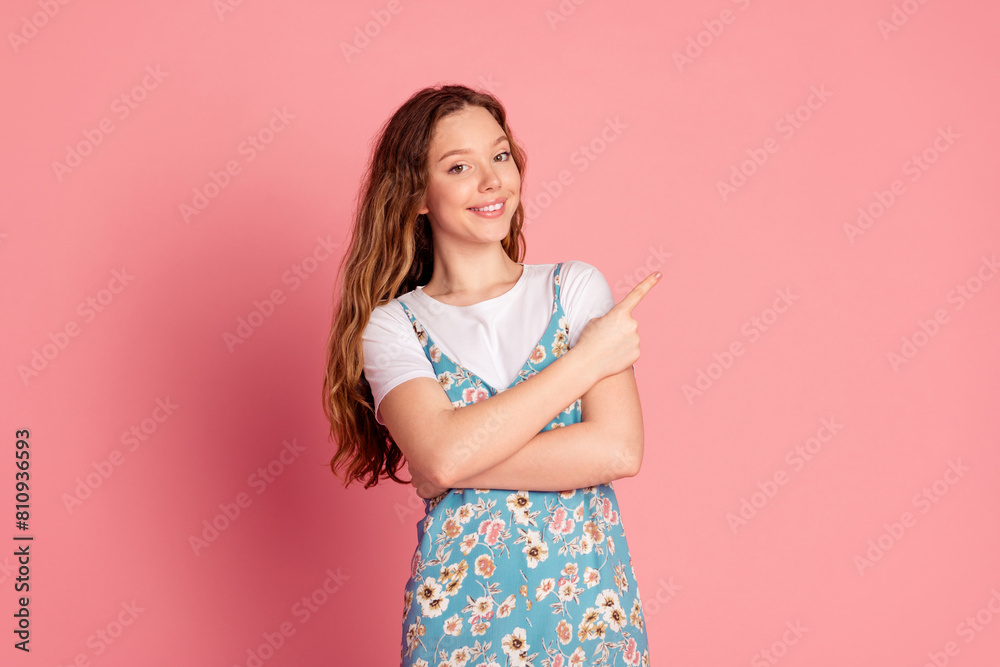 Photo of cute young girl indicate finger empty space wear dress isolated on pink color background Photo of cute young girl indicate finger empty space wear dress isolated on pink color background