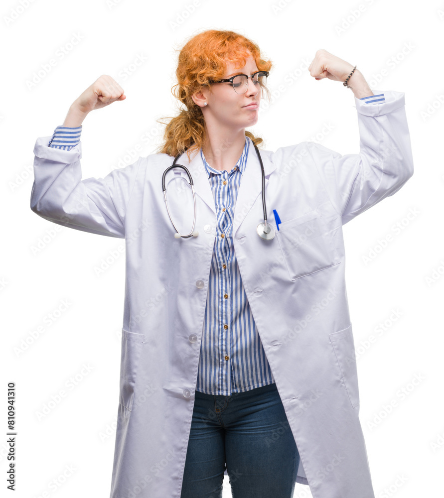 Young redhead woman wearing doctor uniform showing arms muscles smiling proud. Fitness concept. Young redhead woman wearing doctor uniform showing arms muscles smiling proud. Fitness concept.