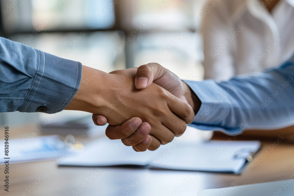 Seated at the table, the accomplished Latin businessman and businesswoman shake hands confidently, affirming their partnership business contract agreement with a gesture of mutual respect during the Seated at the table, the accomplished Latin businessman and businesswoman shake hands confidently, affirming their partnership business contract agreement with a gesture of mutual respect during the