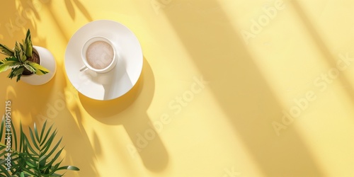 コーヒーと観葉植物の置かれた黄色い机、俯瞰視点
