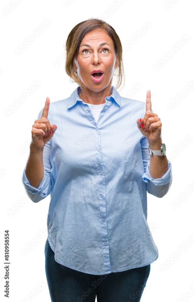 Middle age senior hispanic woman over isolated background amazed and surprised looking up and pointing with fingers and raised arms. Middle age senior hispanic woman over isolated background amazed and surprised looking up and pointing with fingers and raised arms.