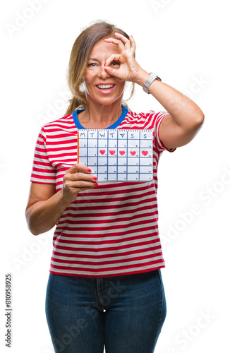 Middle age senior hispanic woman holding menstruation calendar over isolated background with happy face smiling doing ok sign with hand on eye looking through fingers