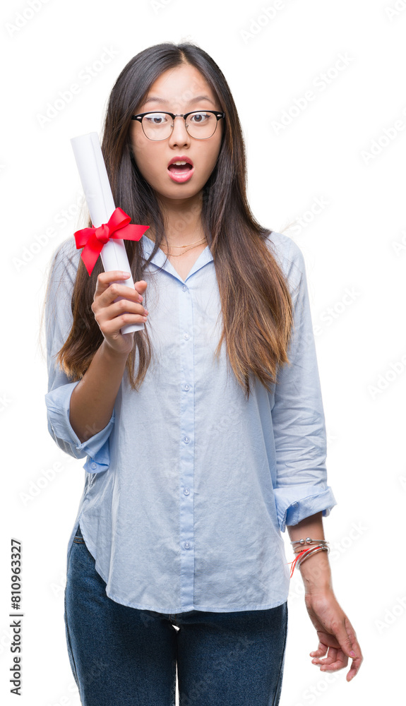 Young asian woman holding degree over isolated background scared in shock with a surprise face, afraid and excited with fear expression Young asian woman holding degree over isolated background scared in shock with a surprise face, afraid and excited with fear expression