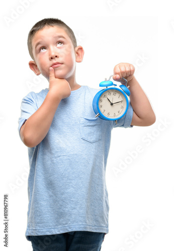 Little child holding alarm clock serious face thinking about question, very confused idea