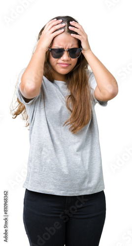 Young beautiful brunette woman wearing sunglasses over isolated background suffering from headache desperate and stressed because pain and migraine. Hands on head.