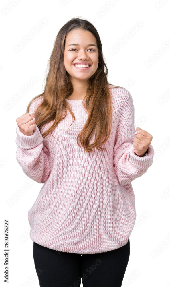 Young beautiful brunette woman wearing pink winter sweater over isolated background celebrating surprised and amazed for success with arms raised and open eyes. Winner concept. Young beautiful brunette woman wearing pink winter sweater over isolated background celebrating surprised and amazed for success with arms raised and open eyes. Winner concept.