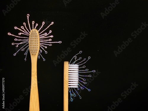 Bamboo toothbrush on black. Dandelion flower drawn on holographic scratch paper. No plastic concept, zero waste.