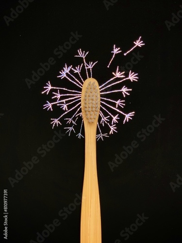 Bamboo toothbrush on black. Dandelion flower drawn on holographic scratch paper. No plastic concept, zero waste.