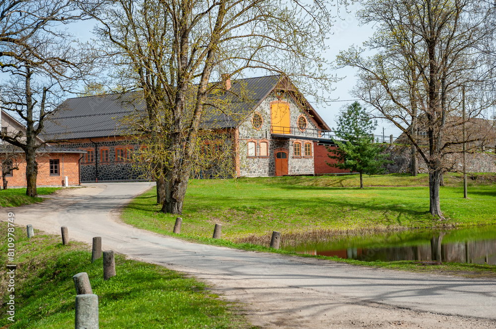 Landscape of barn made of stones and boulders on country road. Rural Latvian landscape with buildings in sunny spring day. Koceni, Latvia, Baltic. Landscape of barn made of stones and boulders on country road. Rural Latvian landscape with buildings in sunny spring day. Koceni, Latvia, Baltic.