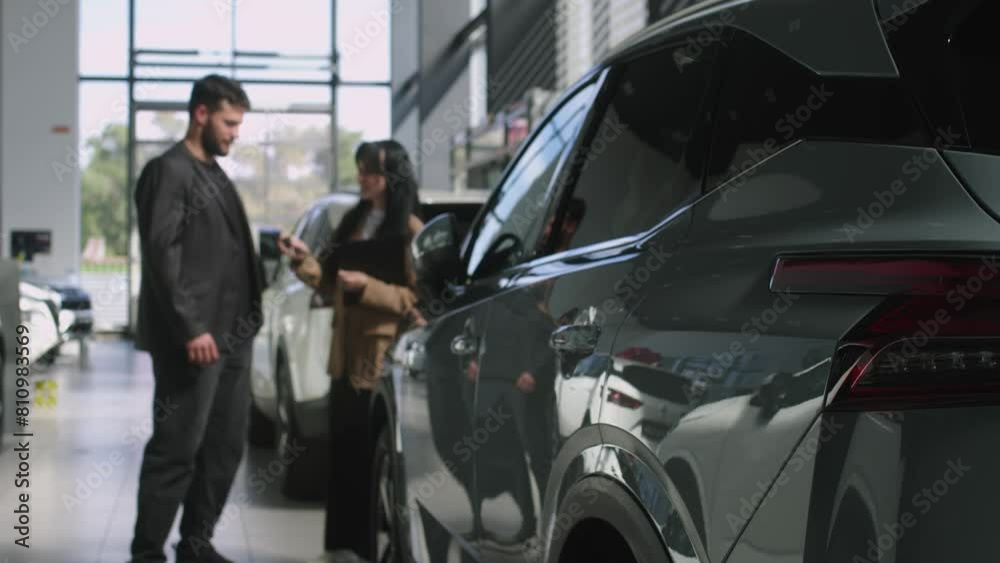 Bearded male buyer selects a car in a car dealership with the help of a car salesman. Concept of buying and selling a car, car rental and car service. Bearded male buyer selects a car in a car dealership with the help of a car salesman. Concept of buying and selling a car, car rental and car service.