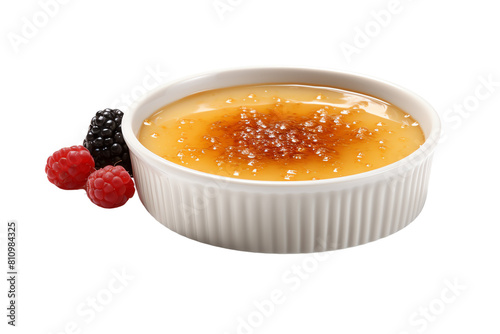 Image shows a white bowl of creme brulee with a hard sugar crust on top and fresh berries on the side.