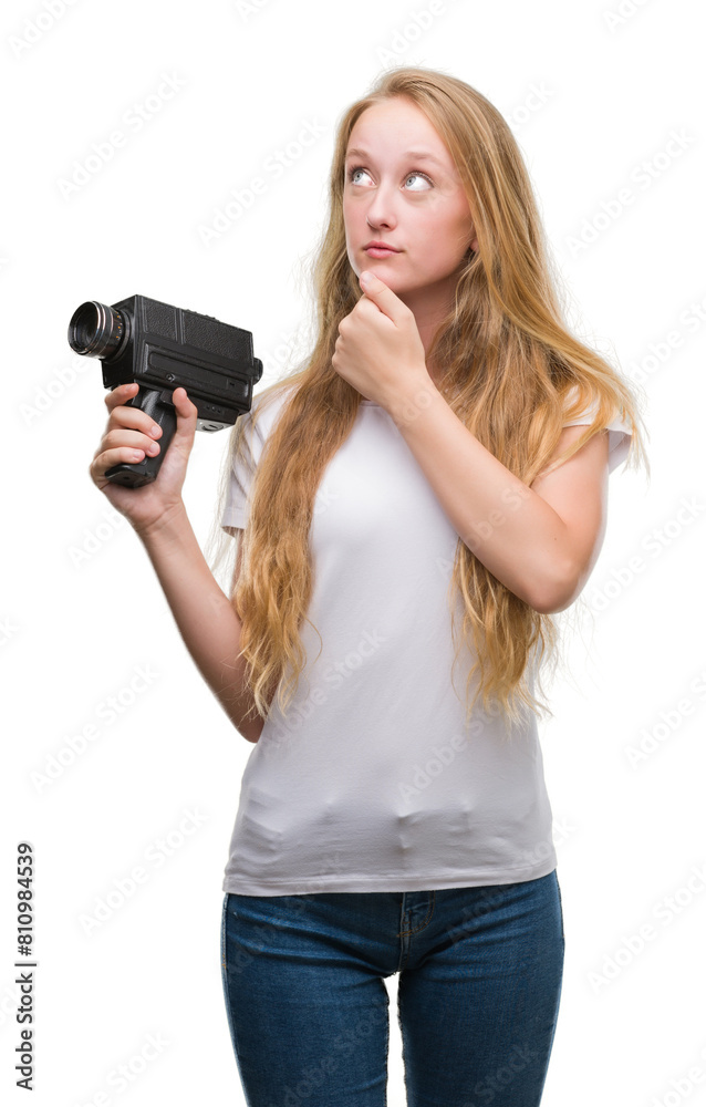 Blonde woman teenager filming holding super 8 video camera serious face thinking about question, very confused idea Blonde woman teenager filming holding super 8 video camera serious face thinking about question, very confused idea